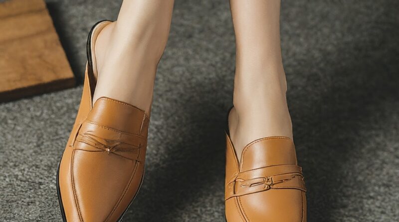 A pair of brown mules for women, worn by a woman who is sitting cross-legged.