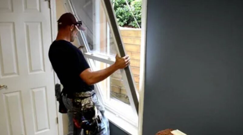 A man carefully installs a window in a residential home, ensuring a secure and precise fit.